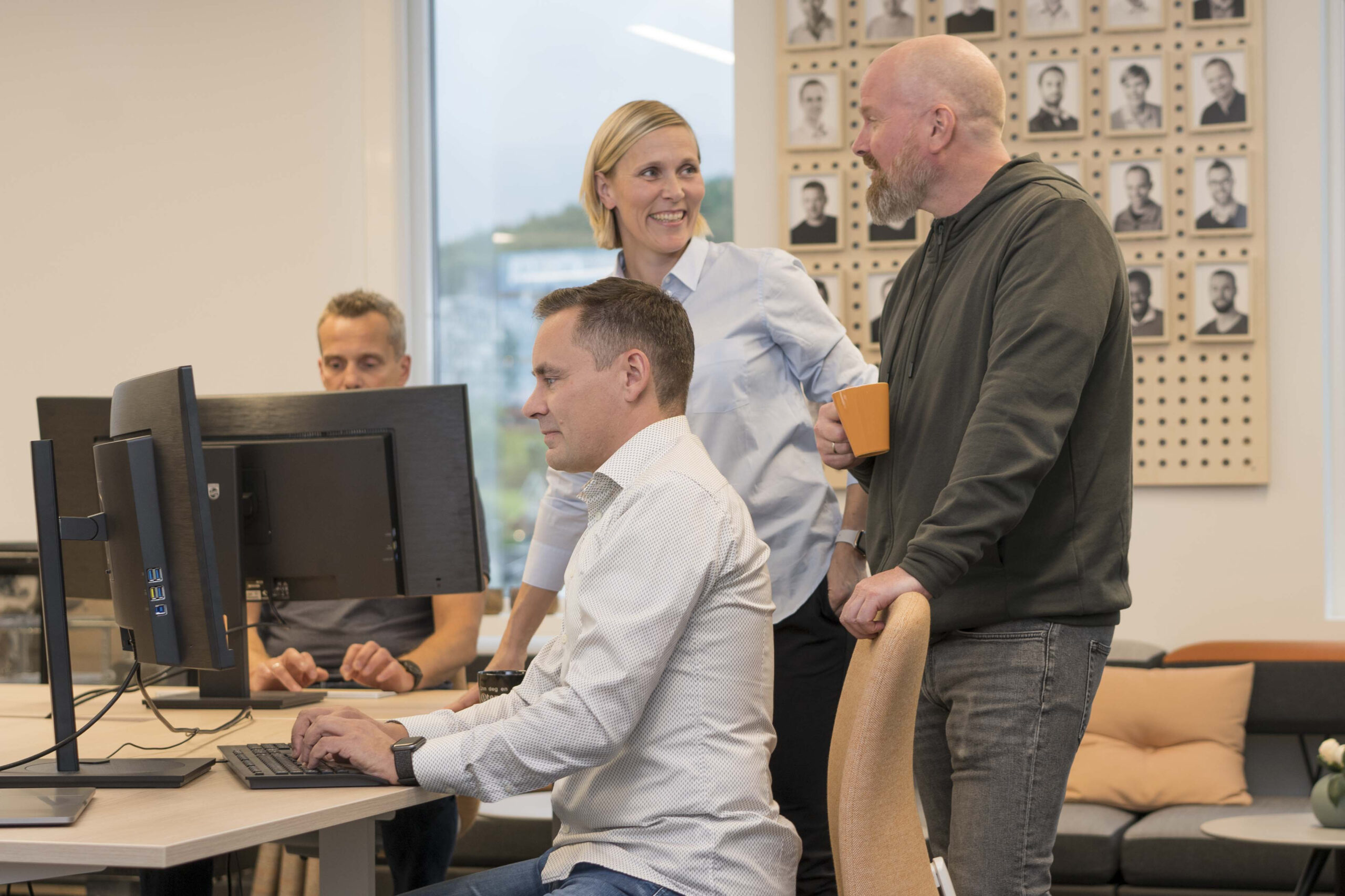 Mennesker snakker sammen ved arbeidsbord med datamaskiner